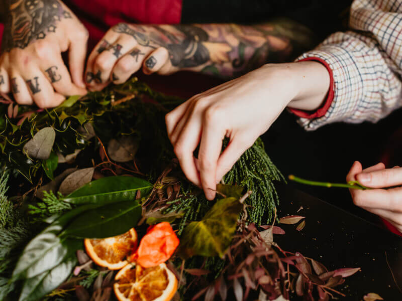 Two hands digging through foliage to make a Christmas wreath.
